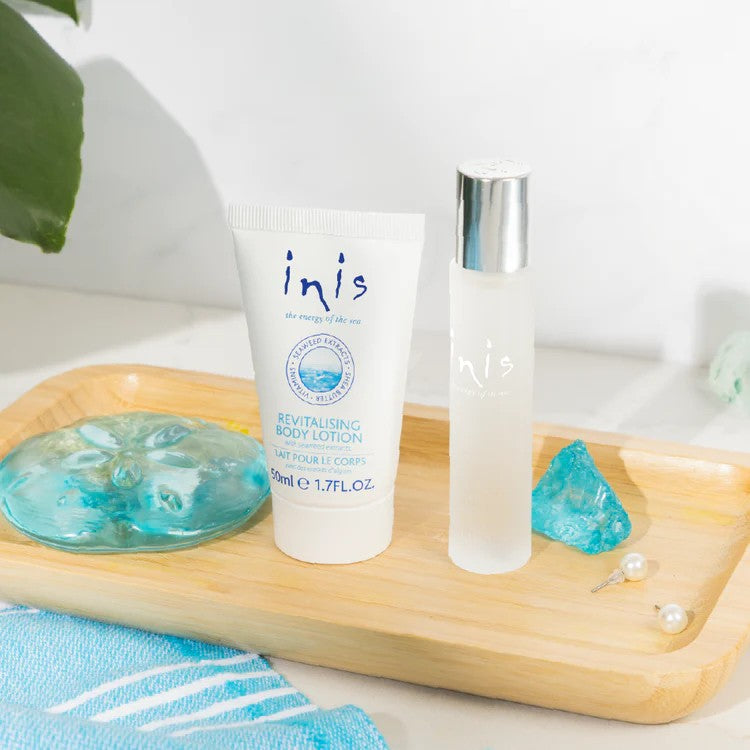 Inis Traveler Duo cologne spray bottle and body lotion tube on bamboo tray with blue accessories and pearl details